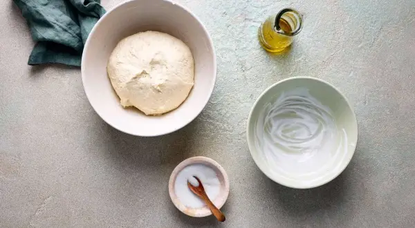 Zutaten für Pfannenbrot mit Joghurt: Teig, Joghurt, Öl und Salz bereitgestellt.