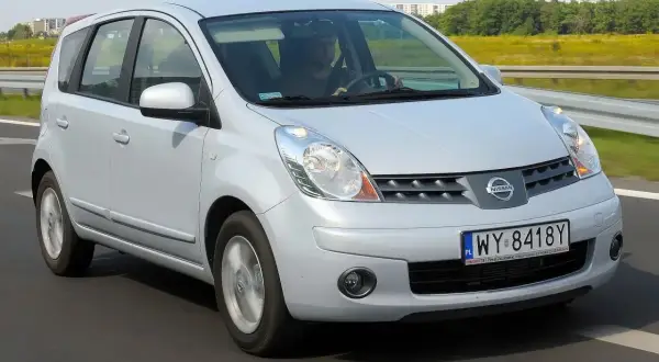 Srebrny Nissan Note E11 w ruchu drogowym. Kierowca w czapce prowadzi auto po asfaltowej drodze.