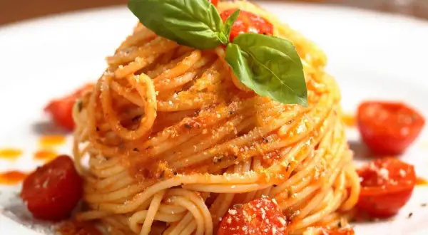 Ein Teller mit köstlichen Spaghetti Aglio e Olio, garniert mit frischem Basilikum und Kirschtomaten.