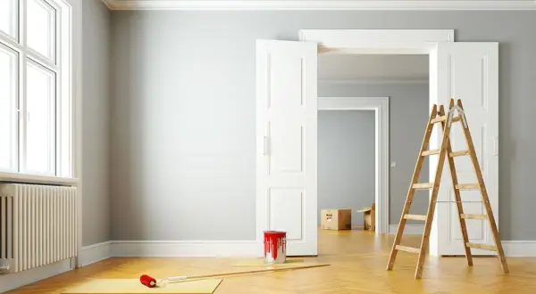 Leere Wohnung bereit zur Renovierung. Ein Farbeimer und eine Leiter stehen bereit, um die Wände zu streichen.