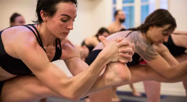 Des pratiquants de hot yoga en pleine concentration, transpirant et étirant leurs corps dans une pièce chauffée.