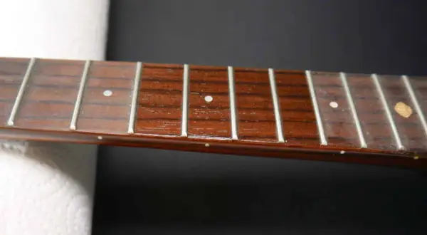 Nahaufnahme des Griffbretts einer Ukulele mit Bundstäbchen und Saiten. Perfekt für Anleitungen zum Ukulele Saiten wechseln.