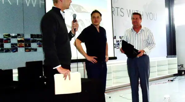 Elon Musk, jeden z tych, kto stworzył Teslę, stoi obok dwóch mężczyzn podczas prezentacji.