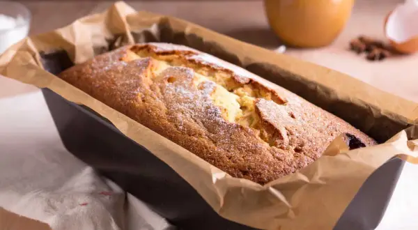 Frisch gebackener Kuchen in einer Kastenform, mit Puderzucker bestäubt. Ein köstlicher Anblick, der zum Reinbeißen einlädt. Dreh dich um, Kuchen, du bist perfekt!