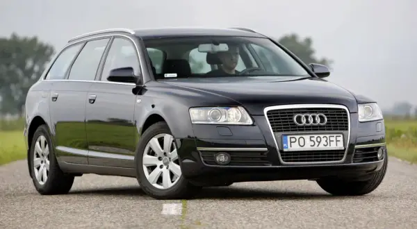 Audi A6 C6 kombi, przygotowanie do wymiany żarówki do jazdy dziennej. Kierowca w kabinie.