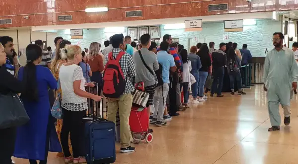 Kolejka podróżnych w hali odlotów, być może na lotnisku AUH Zayed International, oczekujących na odprawę.