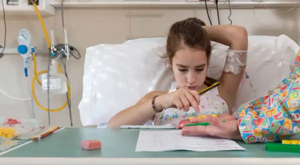 Niña en cama de hospital, con vía intravenosa, jugando con bloques. Un intento de combatir el síndrome de hospitalismo.