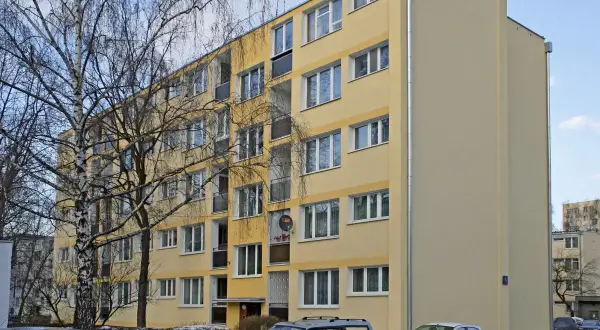 Żółty blok mieszkalny, zimowy dzień. Warto wiedzieć, jak zdać mieszkanie komunalne po śmierci najemcy.