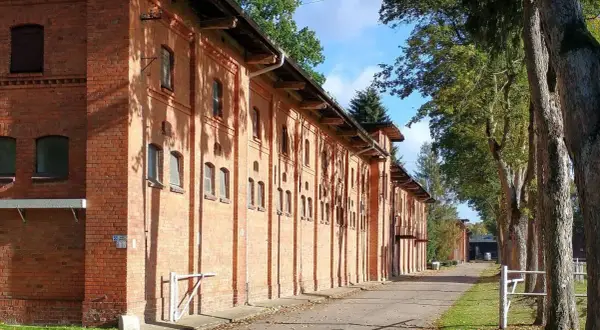 Długa, ceglana stajnia w Starogardzie Gdańskim, gdzie kiedyś stacjonował stado ogierów. Aleja drzew prowadzi do budynków.