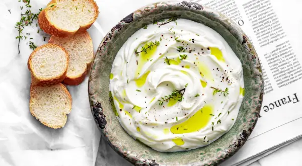 Labneh co to? Kremowy serek jogurtowy z oliwą, pieprzem i tymiankiem, podany z chrupiącymi grzankami. Idealny na śniadanie lub przekąskę.