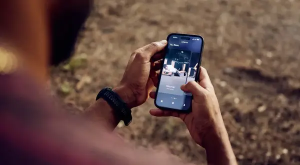 Une application de fitness running s'affiche sur un smartphone tenu par une personne.