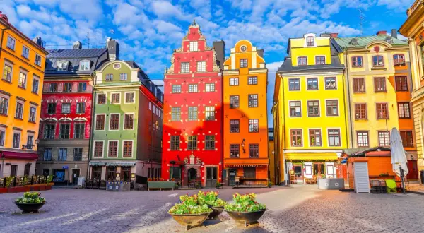 Kolorowe kamienice na placu w Gamla Stan, Sztokholm, pod błękitnym niebem z chmurami.