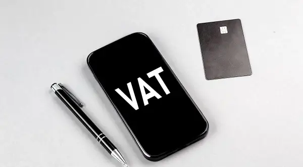 Telefon z napisem VAT, obok długopis i karta płatnicza. Ułatwia to ptu rejestracja.