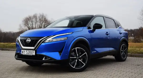 Niebieski Nissan Qashqai e-POWER na brukowanej nawierzchni. Wiele osób szuka nissan qashqai opinie przed zakupem.