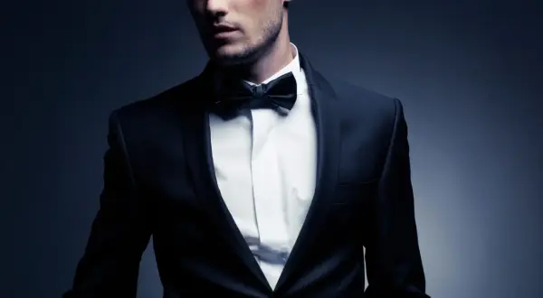 Ein Mann im eleganten Anzug mit Fliege. Der Smoking-Stil unterstreicht seine maskuline Ausstrahlung.