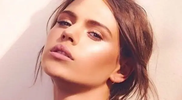 Visage d'une jeune femme au maquillage lumineux, elle pose avec un regard intense. Peut on bronzer avec du maquillage ? Sa peau semble éclatante.