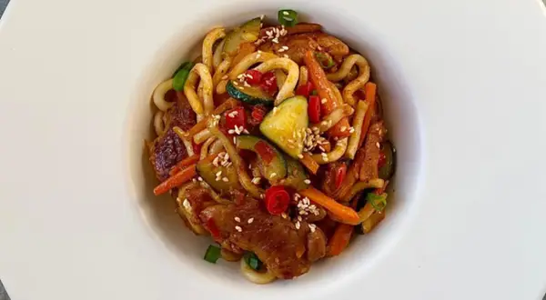 Szybki i tani obiad: makaron udon z kurczakiem, cukinią, marchewką i papryką, posypany sezamem.