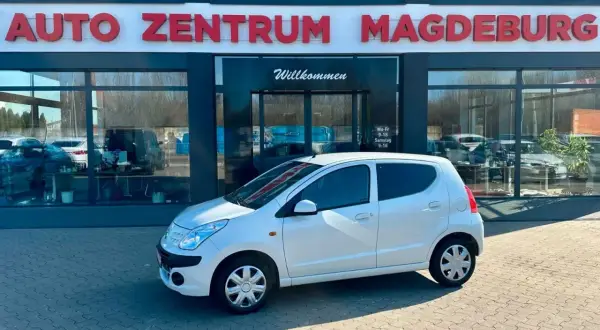 Biały Nissan Pixo zaparkowany przed salonem Auto Zentrum Magdeburg.