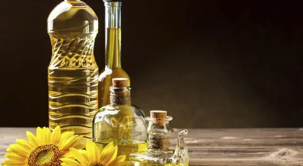 Bottiglie di olio di semi e girasoli. Si può mischiare l'olio d'oliva con l'olio di semi per un sapore unico.