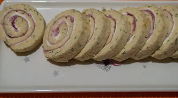 Un roulé au jambon fromage, coupé en tranches, garni de fromage frais et de fines herbes. Parfait pour un apéritif.