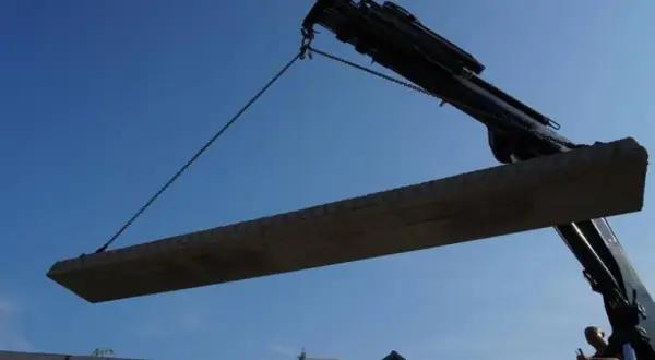 Dźwig podnosi betonowy strop nad budowę.