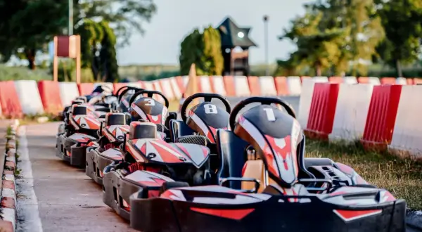 Rząd gokartów z numerami 3, 8 i 1 czeka na torze. Zastanawiasz się, ile kosztują gokarty na taką zabawę?