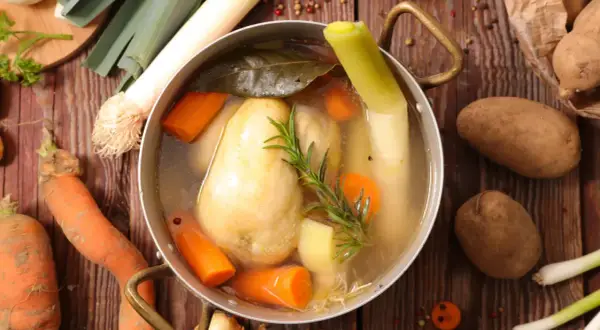 Un plat mijoté de poule au pot, avec carottes, poireaux et pommes de terre, prêt à être dégusté.