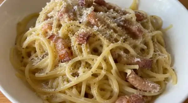 En krämig portion pasta carbonara med knapriga bitar av fläsk och rikligt med svartpeppar.