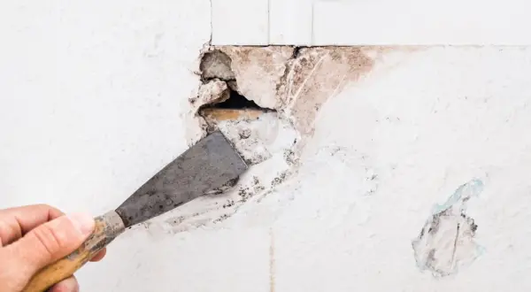 Mano con espátula preparando la pared para como tapar un agujero.