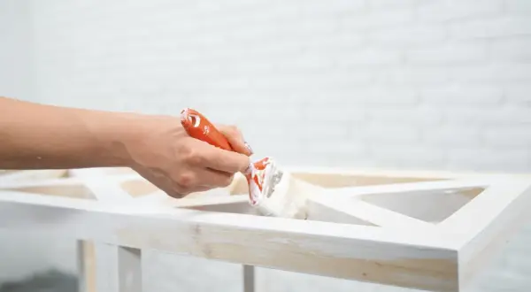 Mano che dipinge un mobile in legno con vernice a gesso, per un effetto shabby chic.