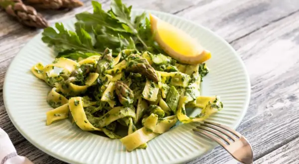 Pappardelle ze szparagami i zielonym pesto, udekorowane rukolą i cytryną. Pyszne danie, które zachwyci każdego miłośnika makaronu.