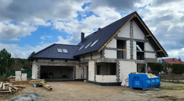 Budowa domu pod klucz w Szczecinie: dom w stanie surowym otwartym, z dachem i oknami dachowymi.