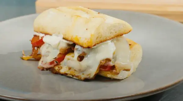 En saftig philly steak sandwich med smält ost och paprika på en tallrik.