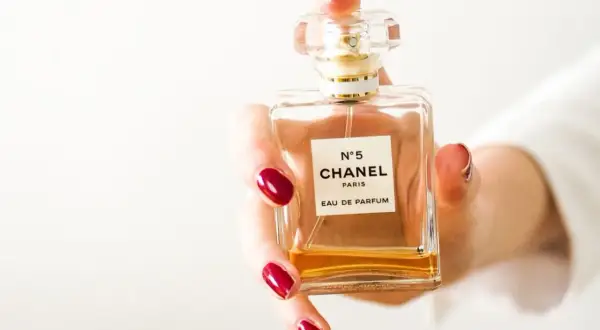Dłoń z czerwonymi paznokciami trzyma flakon Chanel N°5. Czy perfumy mają datę ważności?