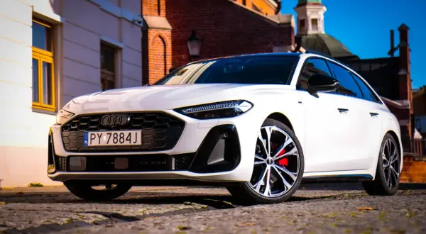 Białe Audi A5 na brukowanej ulicy, z zabytkową architekturą w tle. Zastanawiasz się nad jego spalaniem?