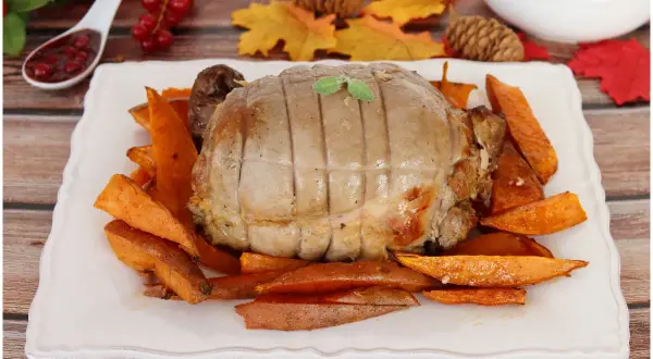 Un succulento arrosto di tacchino, cotto alla perfezione, servito su un letto di patate dolci arrostite. Un piatto autunnale invitante.