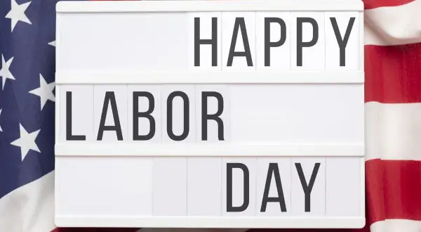 Cartel luminoso con "HAPPY LABOR DAY" sobre bandera de EE.UU. Celebrando el día del trabajador en inglés.