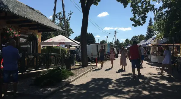Tleń atrakcje: ludzie spacerują po rynku, podziwiając stoiska z rękodziełem i lokalnymi produktami.
