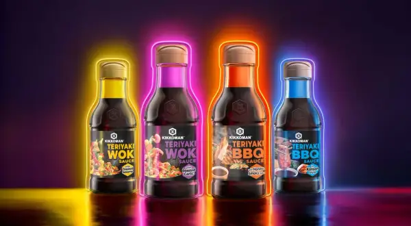 Fyra flaskor Kikkoman teriyaki marinad i olika smaker, omgivna av neonljus.