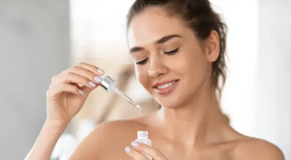 Une femme applique un sérum à la vitamine A rétinol pour une peau éclatante.