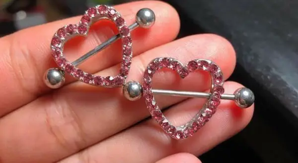 Dwa błyszczące kolczyki w kształcie serca z różowymi cyrkoniami, idealne na nipple piercing.