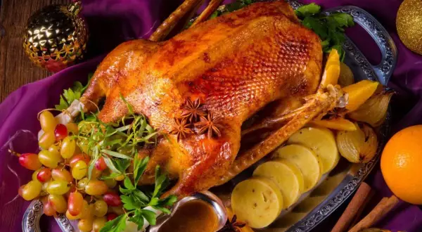 Eine goldbraune Gans auf dem Grill, garniert mit Trauben, Orangen und Sternanis. Perfekt für ein festliches Mahl.