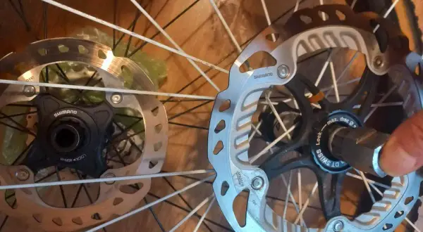 Dwa hamulce tarczowe rowerowe, jeden z mocowaniem center lock Shimano, drugi z mocowaniem center lock DT Swiss.