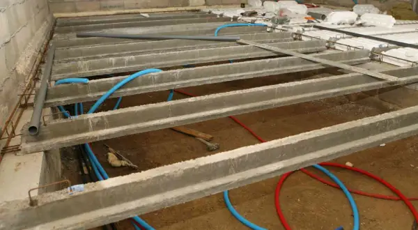 Construction d'un vide sanitaire avec poutrelles béton et tuyaux bleus. Préparation pour comment ventiler un vide sanitaire.