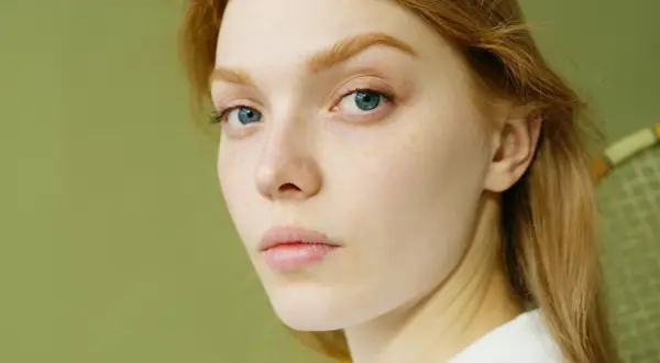 Rostro de mujer joven con pecas y ojos azules. Su cabello es pelirrojo. ¿Glicación qué es? Podría afectar la piel.