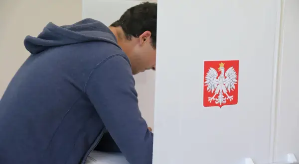 Młody mężczyzna w budce wyborczej, z orłem na ścianie. Czy to symbol jego wyboru, dlaczego młodzi mężczyźni tak chętnie głosują na Konfederację?