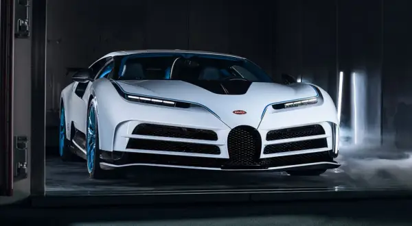 Biały Bugatti Centodieci z niebieskimi akcentami i felgami, otoczony mgłą i pionowymi światłami.