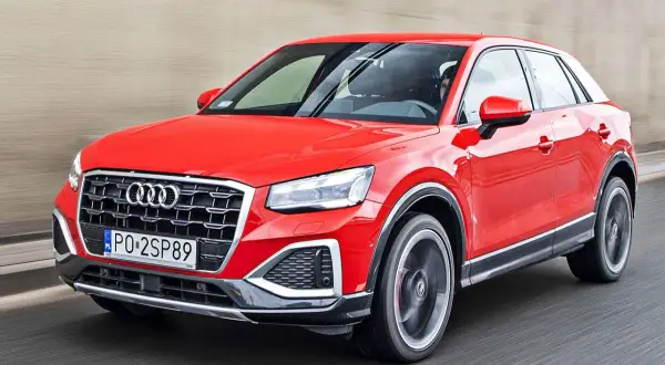 Czerwone Audi Q2 pędzi po drodze, błyszcząc w słońcu.