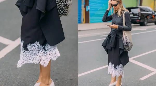 Elegancka koronkowa spódnica stylizacje z czarną marynarką i siatkową torbą. Kobieta w okularach przeciwsłonecznych i szarej bluzce z długim rękawem.
