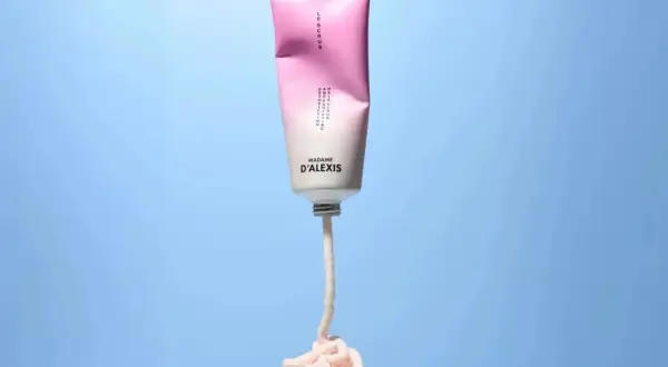Tube de scrub rose et blanc Madame D'Alexis, produit pour un detox cuir chevelu, avec une texture crémeuse qui s'écoule.